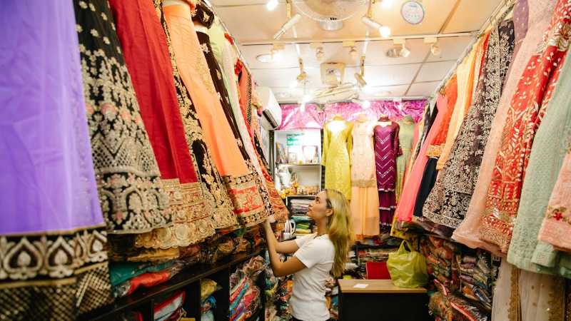 Woman exploring colorful traditional dresses in a boutique store., tags: sarees und - pexel