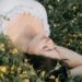 A young woman in a white dress lies peacefully in a field of yellow flowers, exuding tranquility and beauty., tags: und - pexel
